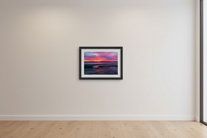 Small fine art landscape print of explosive crimson magenta and orange sunrise sky over Shalda Creek and Lake Michigan with calm water reflections and sandy foreground spit March 9 2023 displayed in modern living room