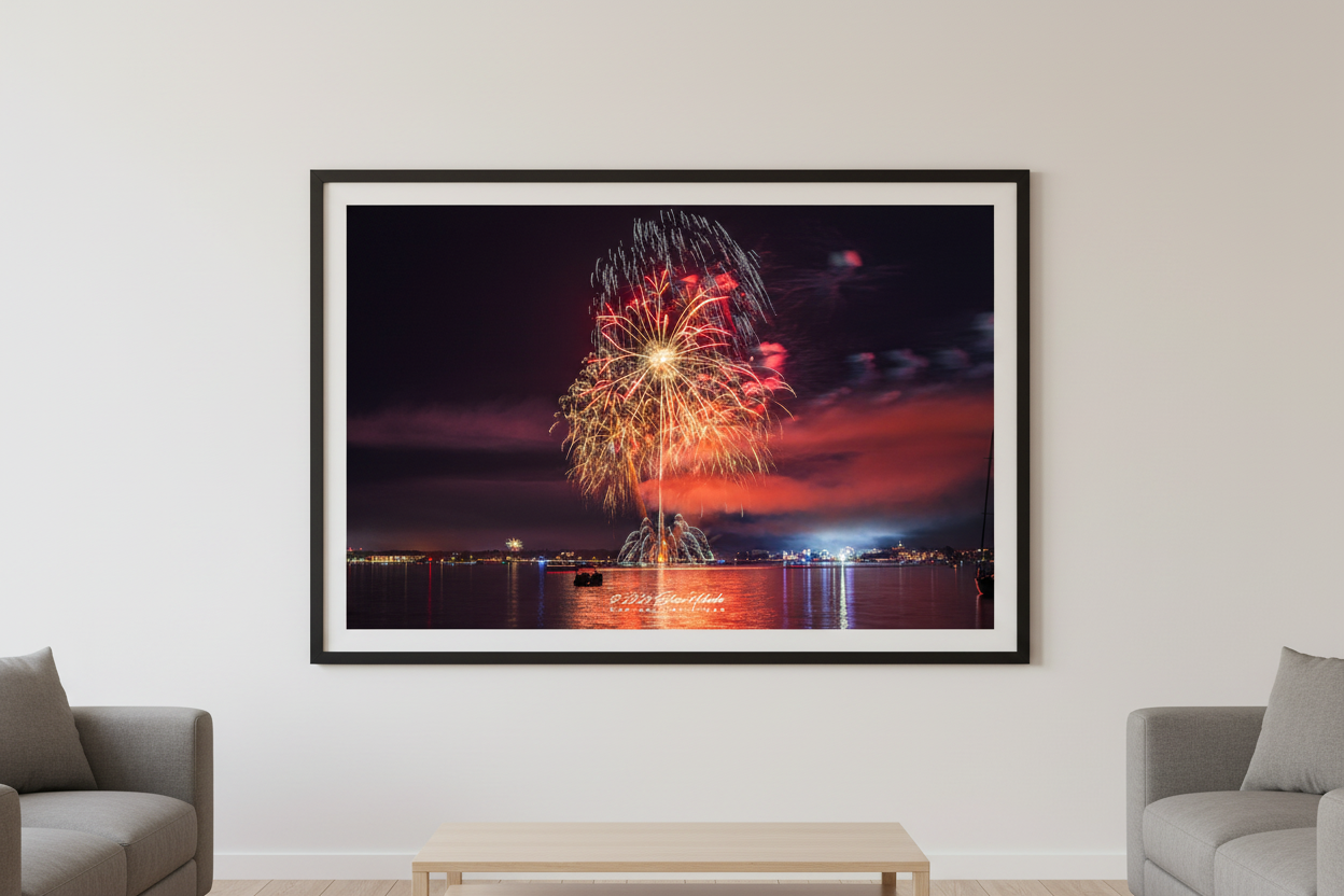 Large fine art landscape print of Traverse City 4th of July 2024 fireworks showing a dramatic crimson sky with vertical rocket trail, golden peony burst, and symmetrical white glitter crown arc over Grand Traverse Bay displayed in modern living room