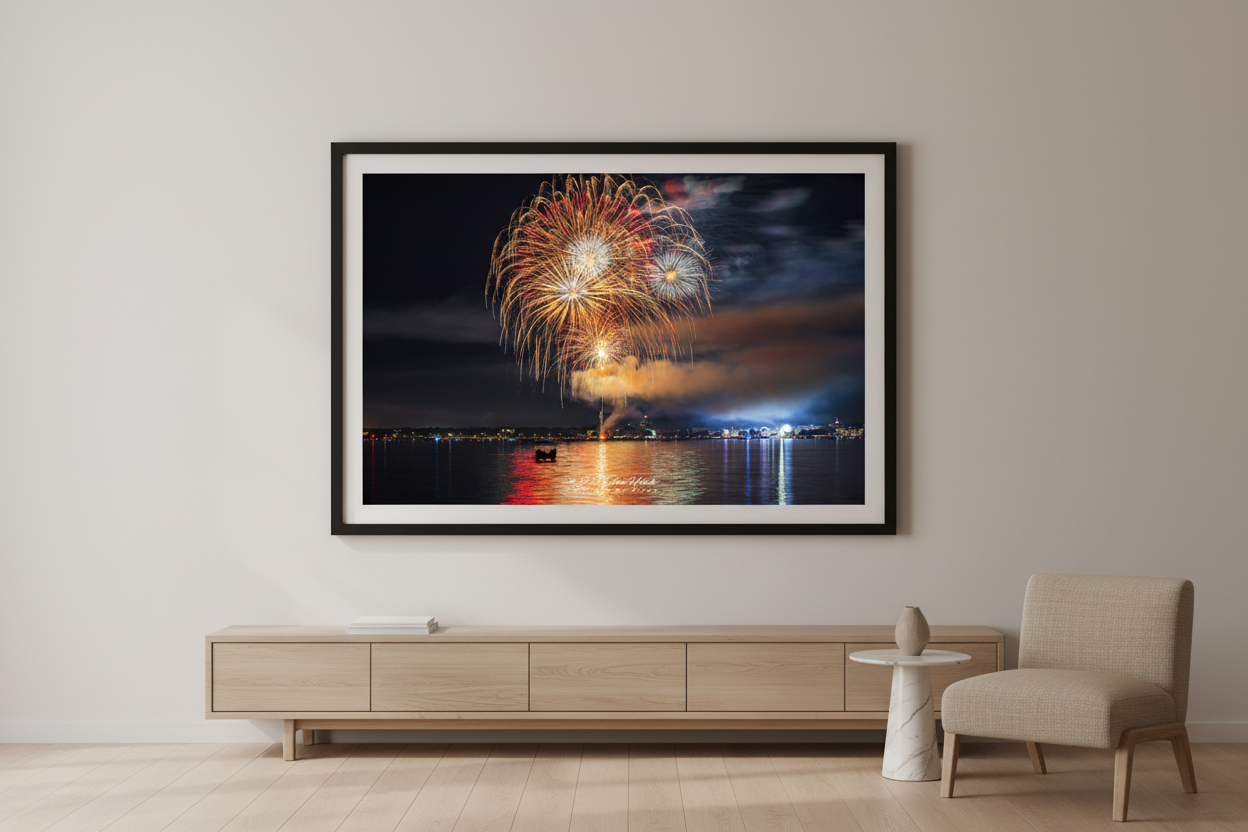 Large fine art landscape print of Traverse City 4th of July 2024 fireworks showing a full spherical gold and crimson peony burst with white starburst core and warm red-gold water reflection over Grand Traverse Bay displayed in modern living room