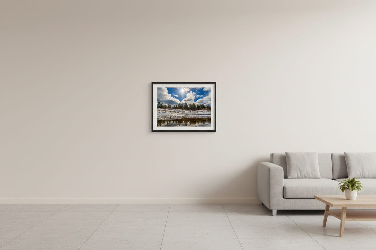 Small fine art landscape print of snow-covered sand dunes with pine treeline and brilliant sunstar reflected in a calm tidal channel at Good Harbor Beach Sleeping Bear Dunes National Lakeshore January 29 2023 displayed in modern living room