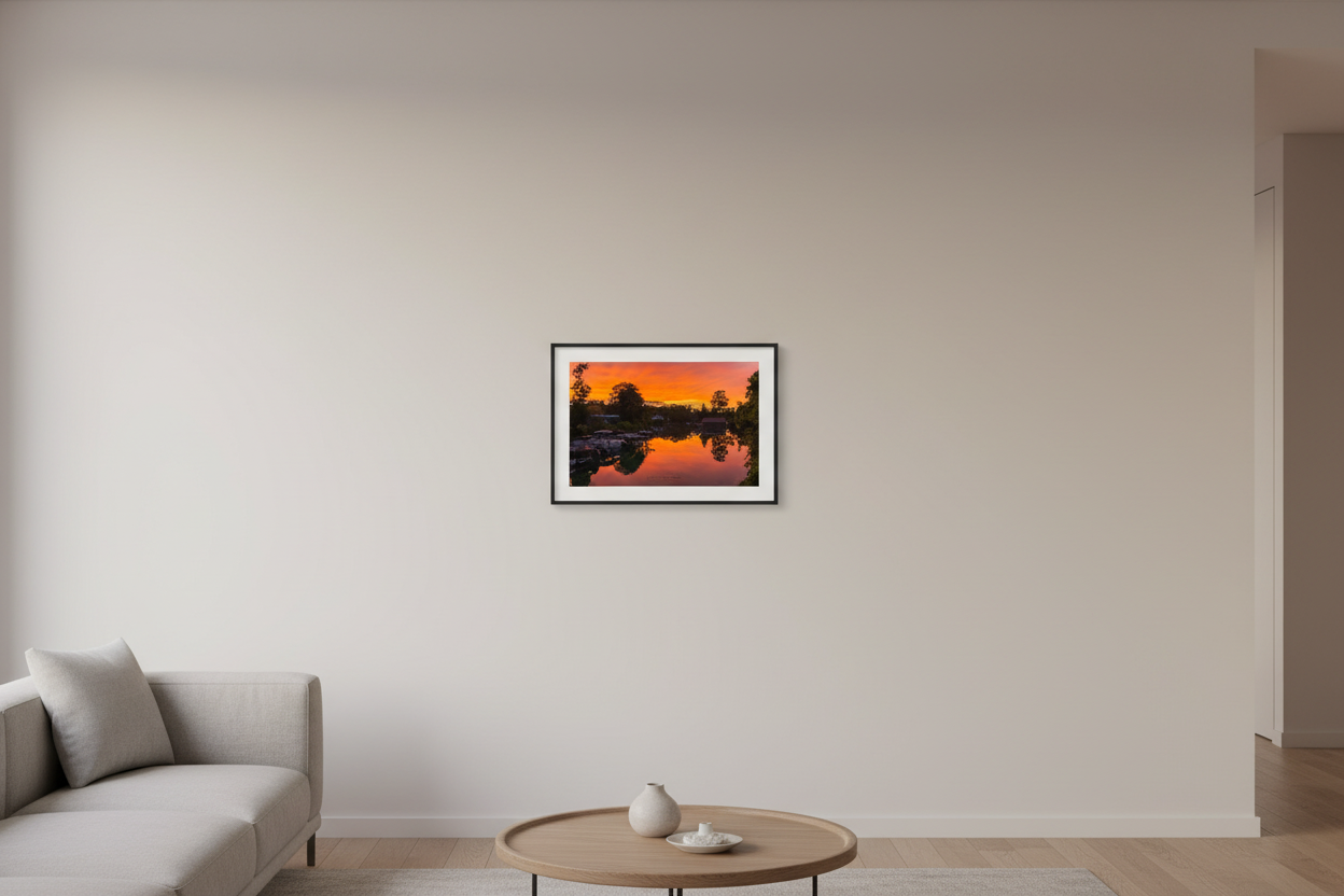 Small fine art landscape print of blazing orange red sunset perfectly mirrored in glassy Leland River with boat docks and tree silhouettes Michigan September 2022 displayed in modern living room