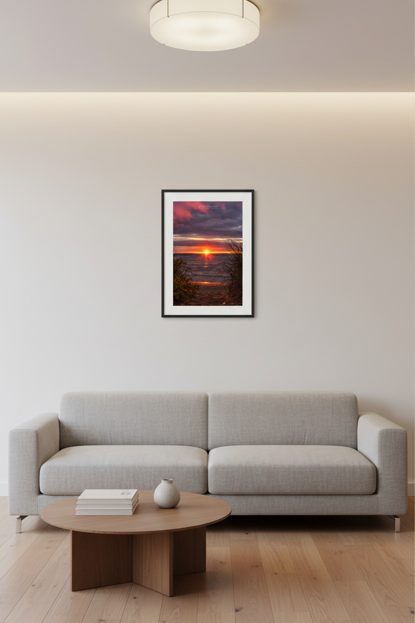Small fine art portrait print of starburst sun on horizon framed by dune grass and beach shrubs with golden reflection path on Lake Michigan Leland May 2024 displayed in modern living room