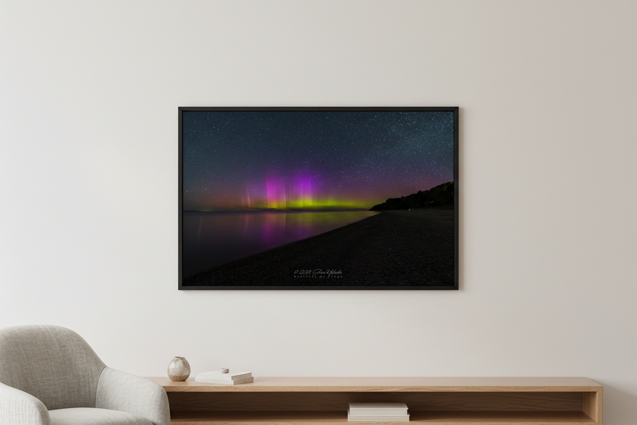 Large fine art landscape print of vivid purple magenta and yellow-green aurora borealis pillars over Lake Michigan from North Street Beach Leland Michigan May 31 2024 displayed in modern living room