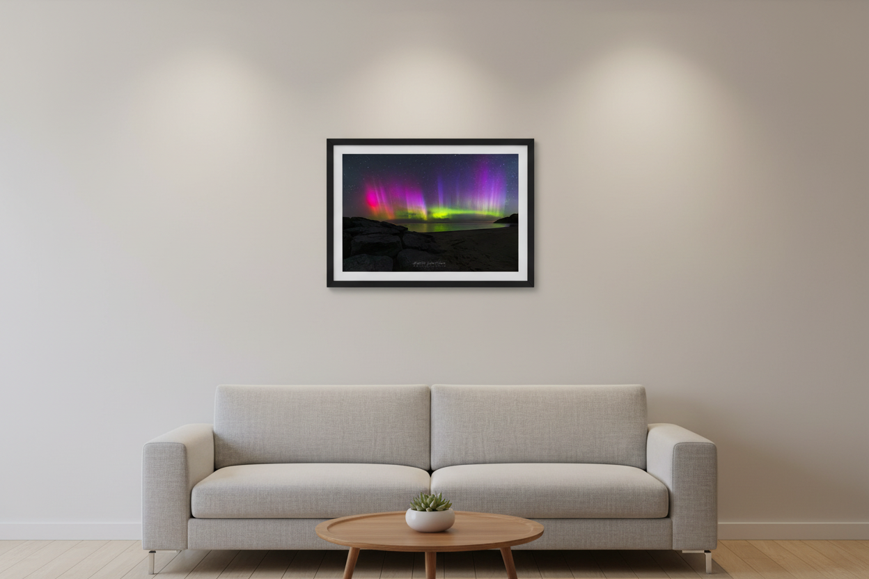 Small fine art landscape print of vivid magenta pink crimson and purple aurora borealis pillars with electric green curtains reflecting over Lake Michigan rocky shoreline at Leland Michigan May 16 2024 at 4:24am displayed in modern living room