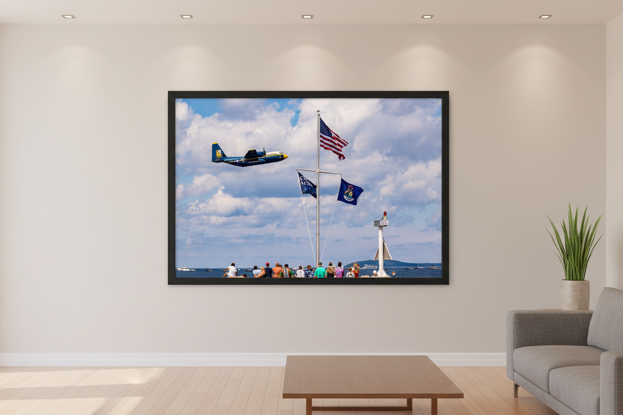 Large fine art landscape print of Blue Angels Fat Albert C-130 flying past a flagpole with US, Cherry Festival, and Michigan state flags over Grand Traverse Bay at the 2024 Traverse City Cherry Festival Airshow displayed in modern living room