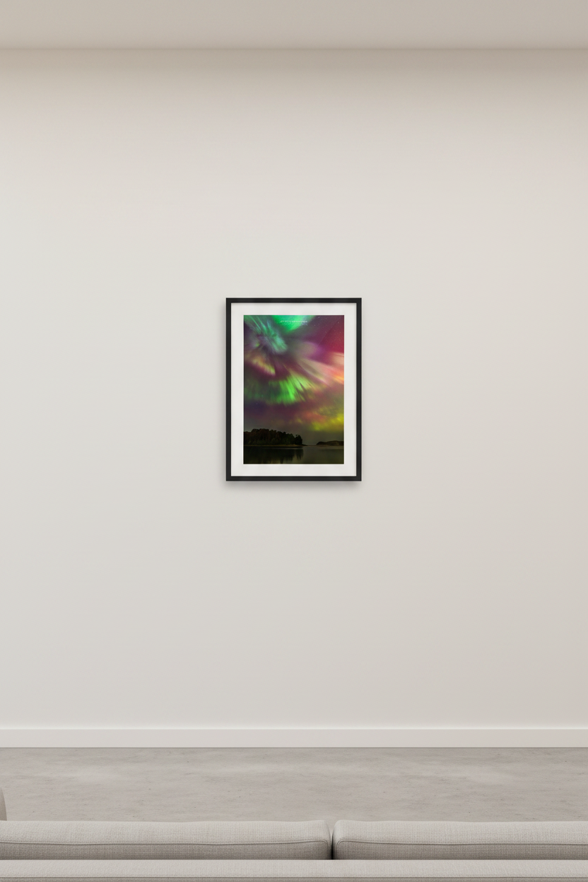 Small fine art portrait print of sweeping full-sky aurora storm with magenta pink green golden yellow and purple curtains over silhouetted tree-covered peninsula reflected in calm water at North Bar Lake Michigan October 11 2024 at 1:10am displayed in modern living room