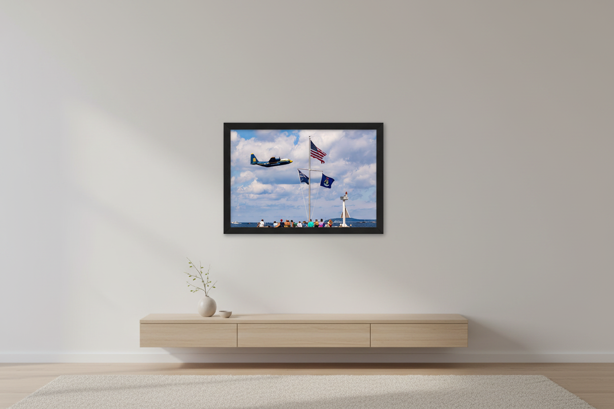 Small fine art landscape print of Blue Angels Fat Albert C-130 flying past a flagpole with US, Cherry Festival, and Michigan state flags over Grand Traverse Bay at the 2024 Traverse City Cherry Festival Airshow displayed in modern living room